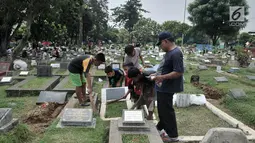 Anak-anak membersihkan makam di TPU Cipinang Baru, Jakarta, Minggu (5/5/2019).  Anak-anak yang mayoritas masih duduk di sekolah dasar ini biasanya melayani jasa Ngoret secara berkelompok dengan tugas masing-masing seperti menyapu dan membersihkan sekitar makam. (merdeka.com/Iqbal S. Nugroho)