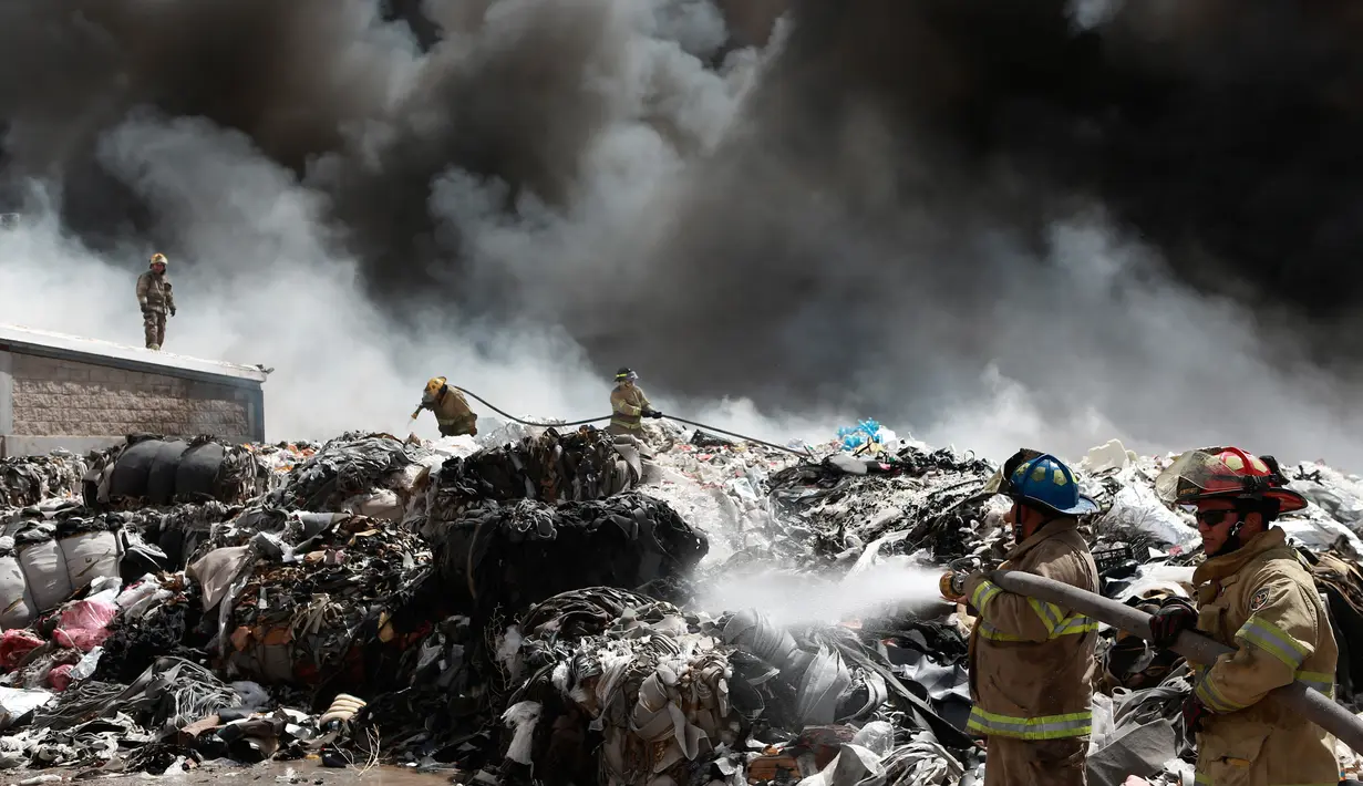 Petugas pemadam kebakaran berusaha memadamkan api di pabrik daur ulang sampah di Ciudad Juarez, Meksiko (2/5). Akibat kebakaran ini pihak berwenang Juarez menyatakan keadaan darurat lingkungan. (AP/Christian Torres)