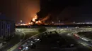 Mobil melaju di jalan saat asap dan api membubung dari fasilitas minyak Aramco menyusul laporan serangan pemberontak Yaman di Jeddah, Arab Saudi, 25 Maret 2022. Pemberontak Yaman mengatakan mereka menyerang fasilitas minyak Arab Saudi tersebut. (AFP)