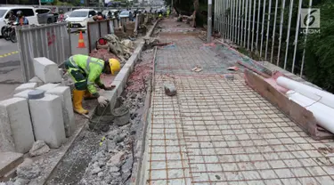 Pekerja menggarap proyek penataan jalur pedestrian di Jalan Gatot Subroto, Jakarta, Selasa (13/3). Penataan ini bertujuan untuk memberi kenyamanan dan keamanan bagi pejalan kaki. (Liputan6.com/Arya Manggala)