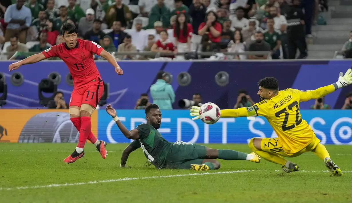 Kiper Timnas Arab Saudi, Ahmed Al Kassar (kanan) berhasil menepis bola hasil tendangan striker Korea Selatan, Hwang Hee-chan pada laga babak 16 besar Piala Asia 2023 di Education City Stadium, Al Rayyan, Qatar, Rabu (31/1/2024) dini hari WIB. (AP Photo/Thanassis Stavrakis)