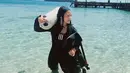 Melihat Prilly bergaya di pantai dengan outfit diving yang lengkap. Bodysuit lengkap berwarna hitam, Prilly berpose memanggul tabung oksigen di bahunya. Foto: Instagram.