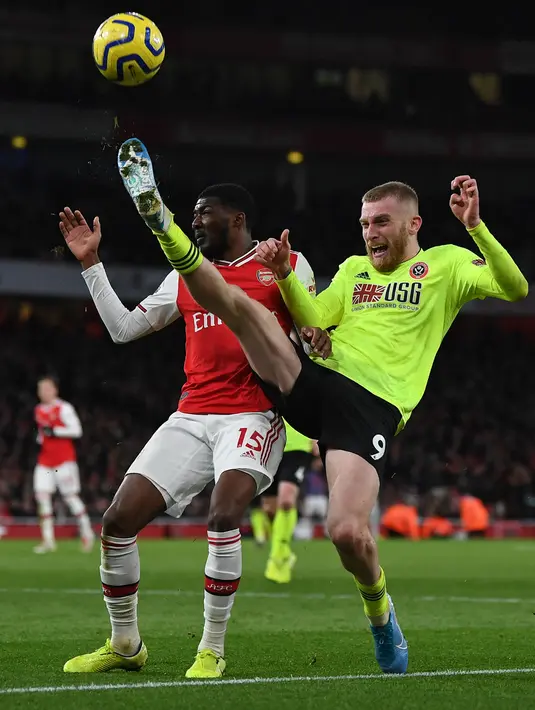 Pemain Sheffield United Oliver McBurnie (kanan) berebut bola dengan pemain Arsenal Ainsley Maitland-Niles pada pertandingan Liga Inggris di Emirates Stadium, London, Inggris, Sabtu (18/1/2020). Pertandingan berakhir 1-1. (Daniel LEAL-OLIVAS/AFP)