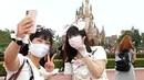 Pengunjung mengenakan masker guna melindungi diri dari virus corona berswafoto saat mengunjungi Tokyo Disneyland di Urayasu, dekat Tokyo, Rabu (1/7/2020). Tokyo Disneyland dibuka kembali untuk pertama kalinya dalam empat bulan setelah sempat ditutup karena penyebaran Covid-19. (AP/ Koji Sasahara)
