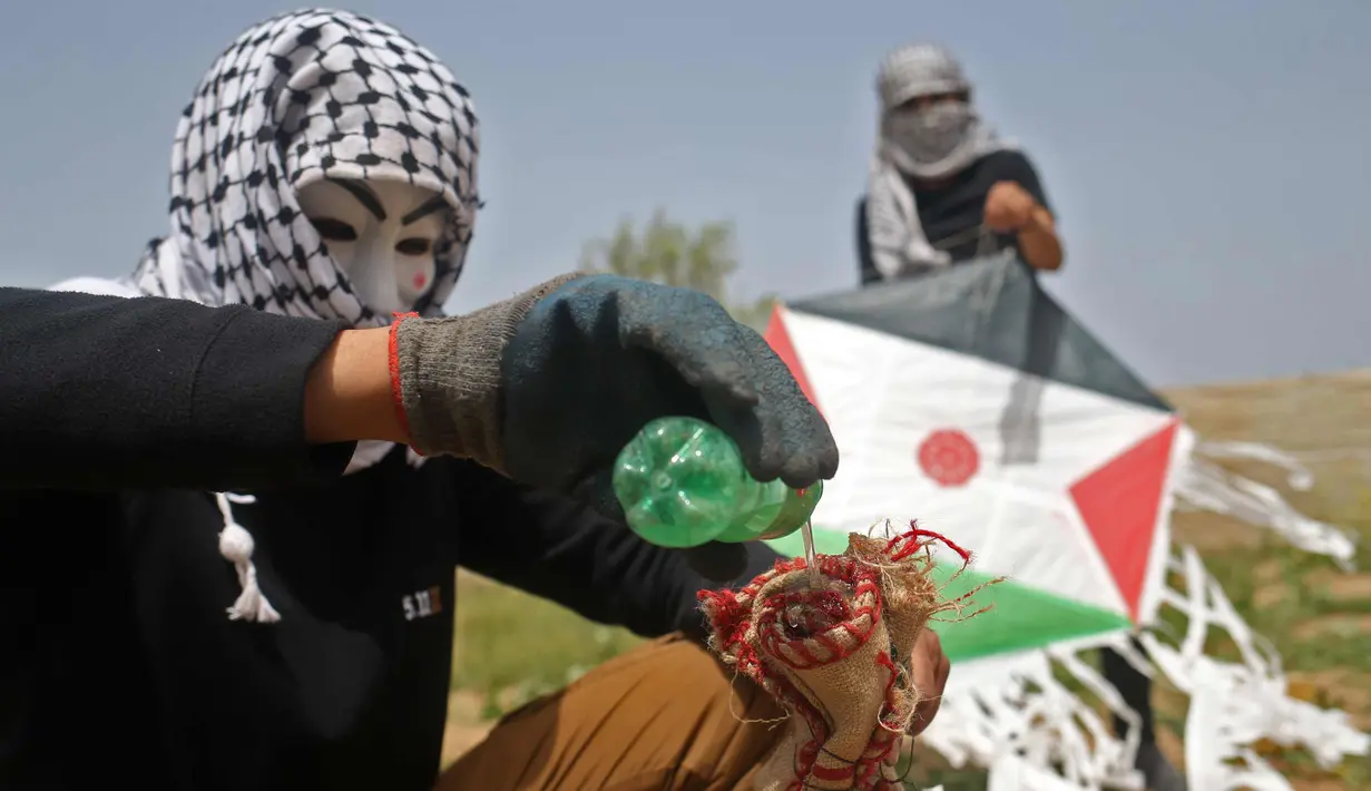 Warga Palestina menyiapkan bom molotov untuk diterbangkan menggunakan layang-layang di atas pagar perbatasan dengan Israel, di pinggiran timur Kota Gaza (20/4). Unjuk rasa warga Palestina terhadap Isrel memasuki minggu keempat. (AFP Photo/Mohammed Abed)
