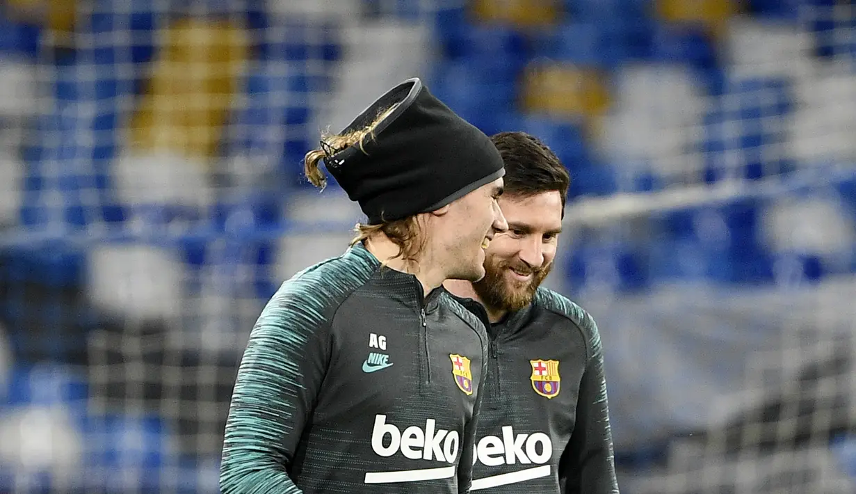 Penyerang Barcelona, Lionel Messi (kanan) berbincang dengan Antoine Griezmann saat menghadiri sesi pelatihan di stadion San Paolo di Naples, Italia (24/2/2020). Barcelona akan bertanding melawan Napoli pada leg pertama babak 16 besar Liga Champions. (AFP/Filippo Monteforte)