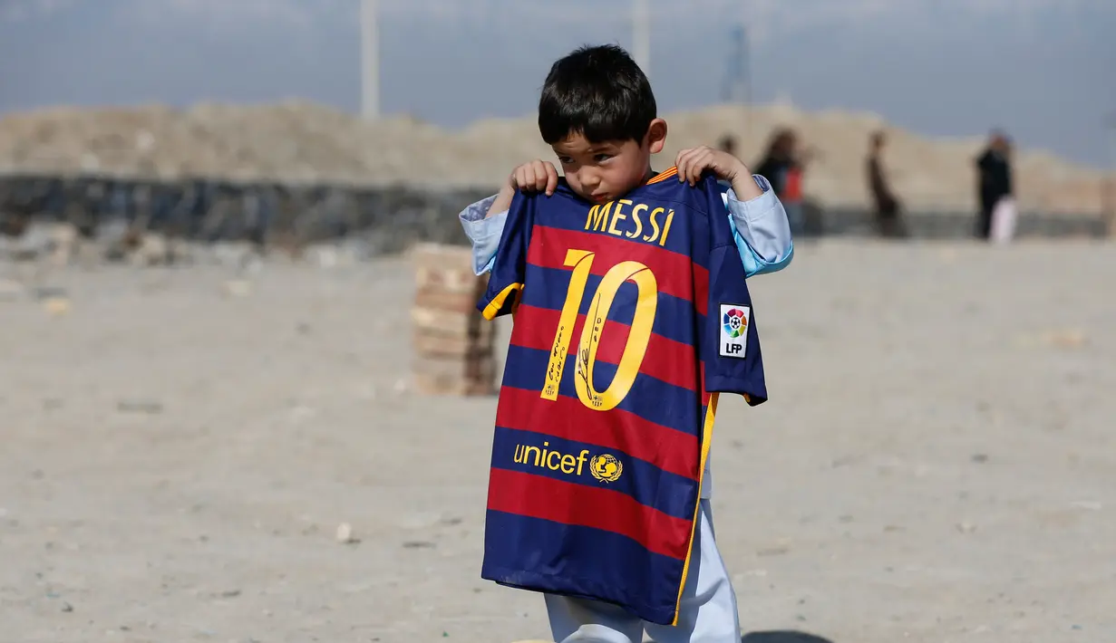 Murtaza Ahmadi (5), bocah asal Afghanistan, menunjukkan jersey yang ditandatangani langsung oleh bintang Barcelona yang juga idolanya, Lionel Messi, sebelum bermain sepak bola di sebuah lapangan terbuka di Kabul, Jumat (26/2). (REUTERS/Omar Sobhani)