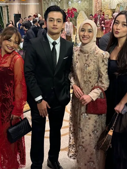 Ada Cut Syifa yang tampil memesona kenakan dress brokat nuansa cream dan handbag merah sebagai statement. [@amelcarla].