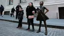 Anak-anak berpose dengan patung Fearless Girl di lokasi barunya di depan bursa efek New York, Selasa (11/12). Kini patung perunggu yang sempat menimbulkan kontroversi itu mendapatkan rumah baru yang lebih permanen. (AP/Mark Lennihan)
