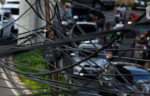 Kendaraan melintas di bawah kabel listrik dan kabel optik yang terlihat semrawut di kawasan Taman Puring, Jakarta, Jumat (3/7/2020). Kesemrawutan kabel ini sering terlihat di sejumlah kawasan Jakarta yang menyebabkan pemandangan kurang enak untuk dilihat. (Liputan6.com/Johan Tallo)