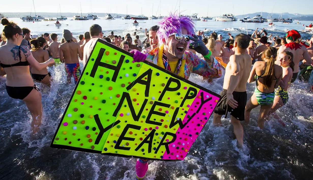 Seorang peserta di English Bay membawa poster saat ambil bagian dari acara tahunan Polar Bear Swim di Vancouver, Kanada (2/1/2016). Meski suhu di pantai tersebut mencapai 3 derajat celcius, mereka tetap antusias. (REUTERS / Ben Nelms)