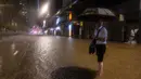 Banjir bandang melanda sejumlah wilayah di Hong Kong. Tampak seorang pejalan kaki menunggu bus di jalan yang tergenang air setelah hujan deras di Hong Kong, Jumat, 8 September 2023. (AP Photo/Louise Delmotte)