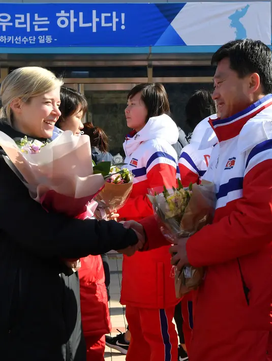 Pelatih tim hoki es wanita Korea Selatan, Saray Murray (kiri) bersalaman dengan pelatih tim hoki es Korea Utara saat tiba di pusat pelatihan nasional Jincheon, Korsel (25/1). (AFP Photo/Pool/ Kyung-Seok)