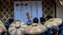 Warga suku asli Baduy memeriksa daftar kandidat di sebuah tempat pemungutan suara sebelum memberikan suara mereka dalam pemilihan presiden dan legislatif di Desa Kanekes, Lebak, provinsi Banten pada 14 Februari 2024. (ADITYA AJI/AFP)