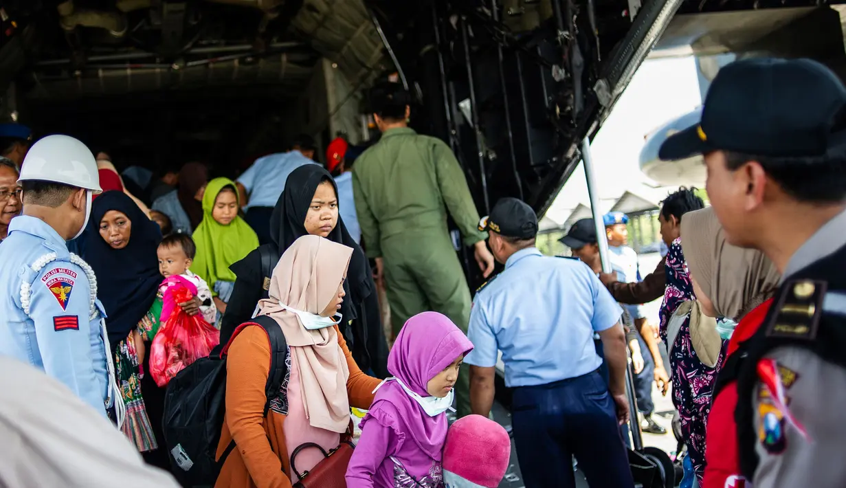Sejumlah warga korban gempa dan tsunami Palu-Donggala turun dari pesawat saat tiba di Surabaya (4/10). Sebanyak 1.411 orang telah dikonfirmasi tewas akibat bencana tersebut. (AFP Photo/Juni Kriswanto)