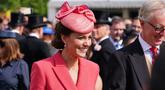 Kate Middleton, Duchess of Cambridge dari Inggris berbicara kepada para tamu di Pesta Taman Kerajaan di Istana Buckingham di London (18/5/2022). Kate Middleton tampak anggun dalam gaun mantel versi koral berwarna merah muda. (AFP/Pool/Dominic Lipinski)