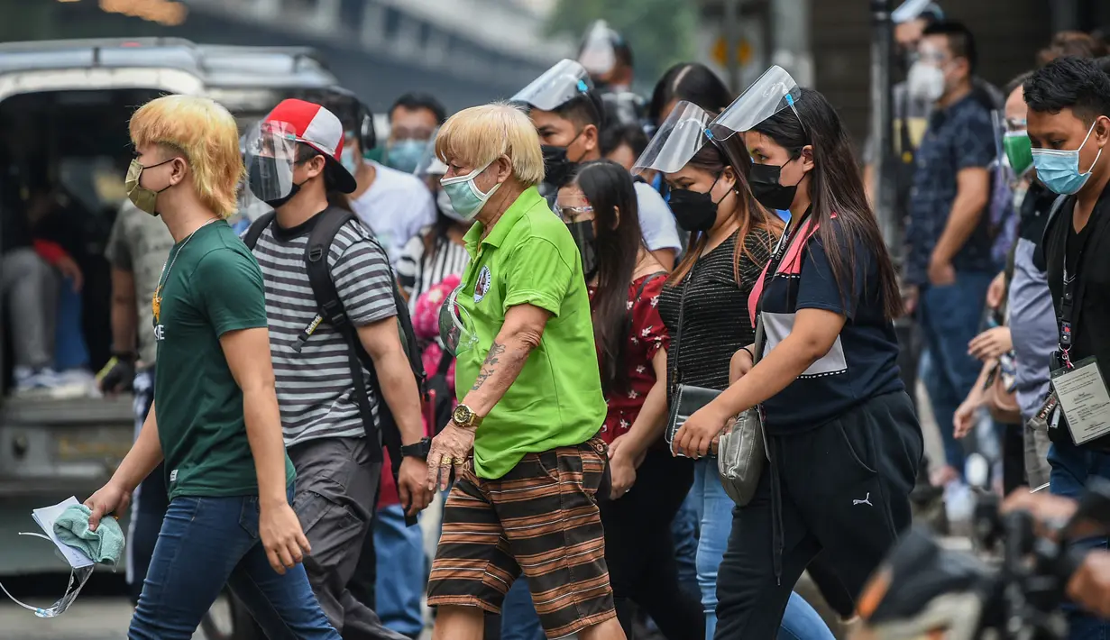 Orang-orang yang mengenakan masker menyeberang jalan di Manila, sehari sebelum pihak berwenang mencabut perintah tinggal di rumah pada Selasa (7/9/2021). Filipina akan mencabut lockdown di ibu kota Manila pada Rabu (8/9), saat kasus corona harian naik dua kali lipat. (Ted ALJIBE/AFP)