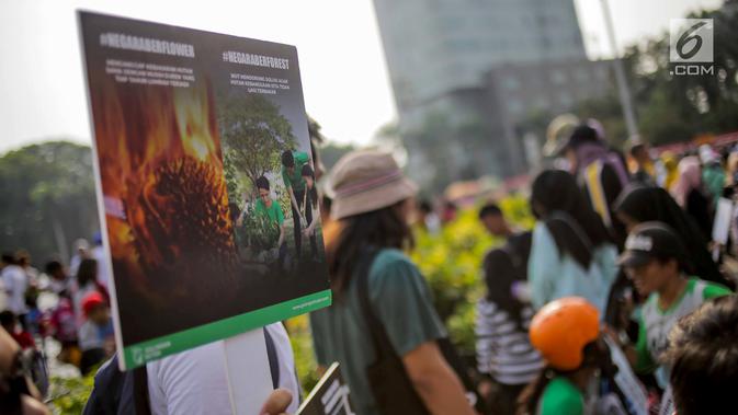 Anggota Walhi Jakarta membawa poster saat menggelar aksi melawan asap dan peduli satwa dalam CFD di Bundaran HI, Jakarta, Minggu (15/9/2019). Walhi menuntut pemerintah segera menyelesaikan permasalahan kebakaran hutan yang berdampak buruk bagi manusia dan lingkungan. (Liputan6.com/Faizal Fanani)