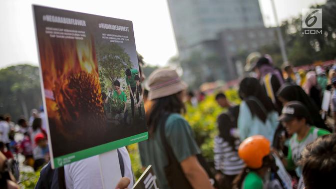 Anggota Walhi Jakarta membawa poster saat menggelar aksi melawan asap dan peduli satwa dalam CFD di Bundaran HI, Jakarta, Minggu (15/9/2019). Walhi menuntut pemerintah segera menyelesaikan permasalahan kebakaran hutan yang berdampak buruk bagi manusia dan lingkungan. (Liputan6.com/Faizal Fanani)