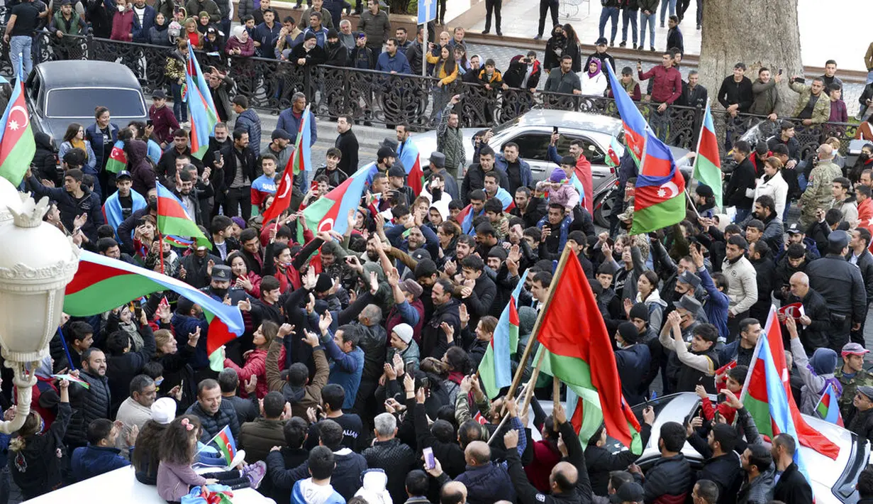 Rakyat Azerbaijan mengibarkan bendera nasional di Ganja, Azerbaijan, Selasa (10/11/2020). Armenia dan Azerbaijan mengumumkan perjanjian damai untuk menghentikan pertempuran atas wilayah Nagorno-Karabakh di Azerbaijan berdasarkan pakta yang ditandatangani dengan Rusia. (AP Photo/Aydin Mammedov)