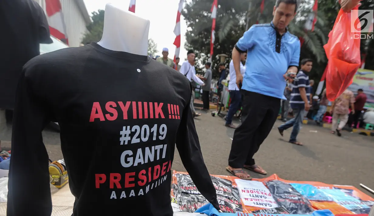 Calon pembeli melihat kaos #2019GantiPresiden di halaman Masjid Istiqlal, Jakarta, Jumat (10/8). Pedagang menjual kaos lengan panjang dan pendek berwarna putih, hitam, biru dan merah. (Liputan6.com/Fery Pradolo)