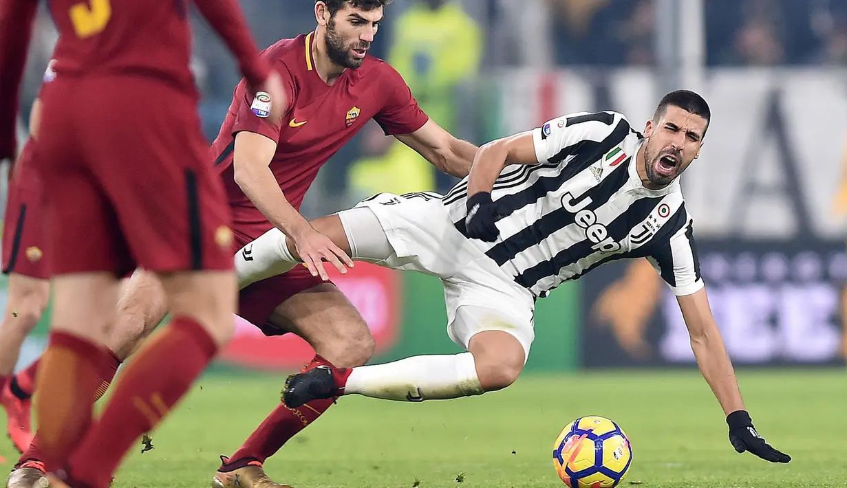Pemain Juventus, Sami Khedira terjatuh saat berebut bola dengan pemain Roma, Federico Fazio saat pertandingan Liga Italia di Turin, Italia (23/12). Pada pertandingan ini Juventus menang 1-0 atas Roma. (Alessandro Di Marco / ANSA via AP)