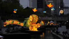 Pengunjung yang mengenakan masker untuk membantu mengekang penyebaran virus corona beristirahat di dekat lentera yang ditampilkan untuk merayakan ulang tahun Buddha yang akan datang pada 8 Mei, di aliran publik di Seoul, Korea Selatan, Selasa, 26 April 2022. (AP Photo /Lee Jin-man)