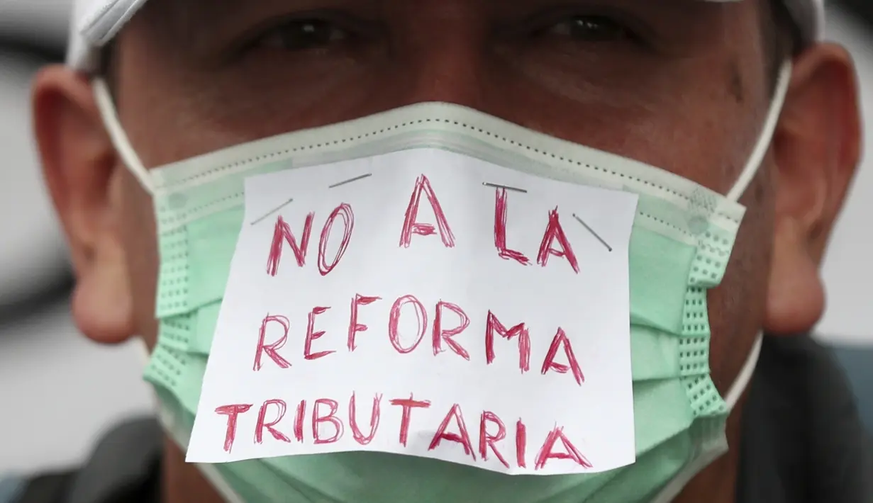 Seorang pria yang mengenakan masker dengan teks bertuliskan "Tanpa Reformasi Pajak" dalam bahasa Spanyol melakukan aksi unjuk rasa memprotes reformasi pajak yang diusulkan pemerintah, di ibu kota Kolombia, Bogota, pada Rabu (28/4/2021). (AP Photo/Fernando Vergara)