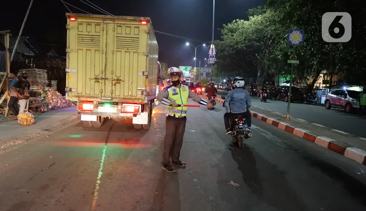 Petugas kepolisian mengatur arus lalu lintas di posko penyekatan mudik di Kedungwaringin, Kabupaten Bekasi, Senin (10/5/2021). Pada H-3 menjelang Idul Fitri 1442 H, jumlah petugas yang berjaga di pos penyekatan pemudik di Kedungwaringin, ditambah sebanyak 150 orang. (Liputan6.com/Herman Zakharia)