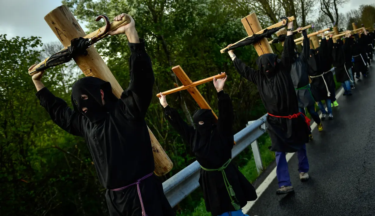 Sejumlah peninten mengenakan topeng membawa salib saat ritual musim semi '' Romeria Cruceros de Arce '' di Spanyol utara (13/5). Mereka berjalan memikul salib dari kota kecil Pyrenees menuju Gereja Roncesvalles. (AP / Alvaro Barrientos)