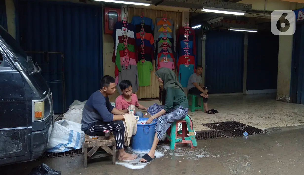 Warga mencuci barang-barang usai banjir merendam Pasar Cipulir, Jakarta, Jumat (3/1/2020). Meski banjir telah surut, akitivitas jual beli di Pasar Cipulir masih belum kembali normal. (Liputan6.com/Angga Yuniar)