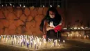 Emi Godoy menyalakan lilin untuk mengenang suaminya Sinforiano Roa yang meninggal karena komplikasi COVID-19, di depan Kementerian Kesehatan di Asuncion, Paraguay, Minggu (14/3/2021). Orang-orang menyalakan lilin untuk memberi penghormatan kepada 3.450 korban COVID-19. (AP Photo/Jorge Saenz)