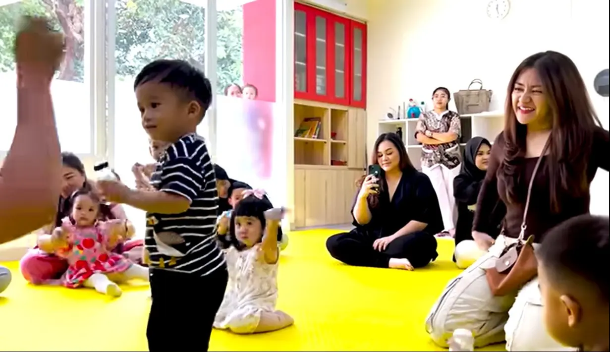 Baby Adzam tampak aktif mengikuti beberapa kegiatan anak-anak. Baik bermain, bernyanyi hingga joged-joged. Tingkah keduanya juga membuat warganet makin gemas dan terhibur.  [Youtube/NATHALIE HOLSCHER]