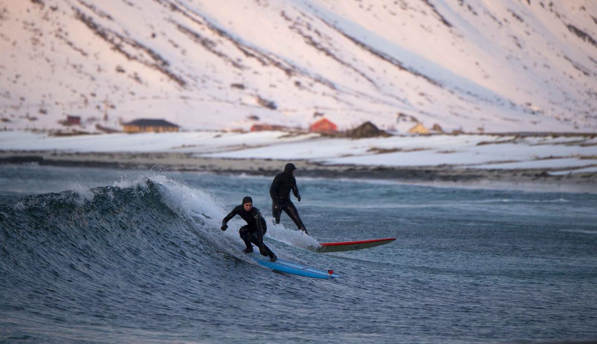 Peselancar beraksi dengan temperatur laut berkisar 5-65-6 ∞C dan juga temperatur udara   0∞C. di kawasan pantai  Flackstad, dekat Ramberg, kepulauan Lofoten, Arctic Circle, (10/3/2016). (AFP/Olivier Morin)