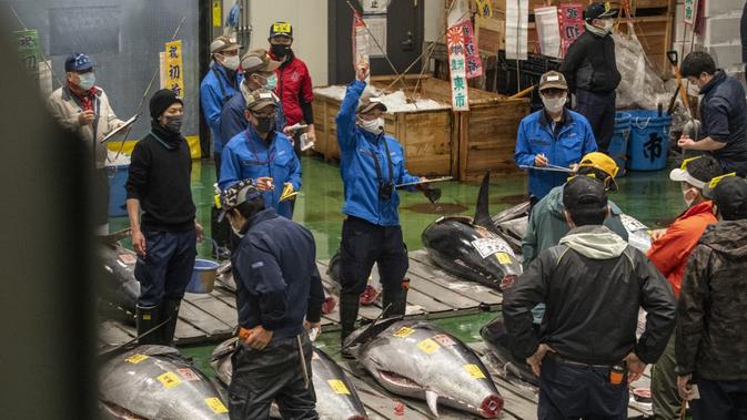 Para tengkulak yang mengenakan masker untuk mencegah penularan COVID-19 berpartisipasi dalam lelang tuna di Pasar Toyosu, Tokyo, Jepang, 5 Januari 2021. Untuk lelang tahun ini, penonton tidak diizinkan untuk menghadiri acara tersebut. (Philip FONG/AFP)