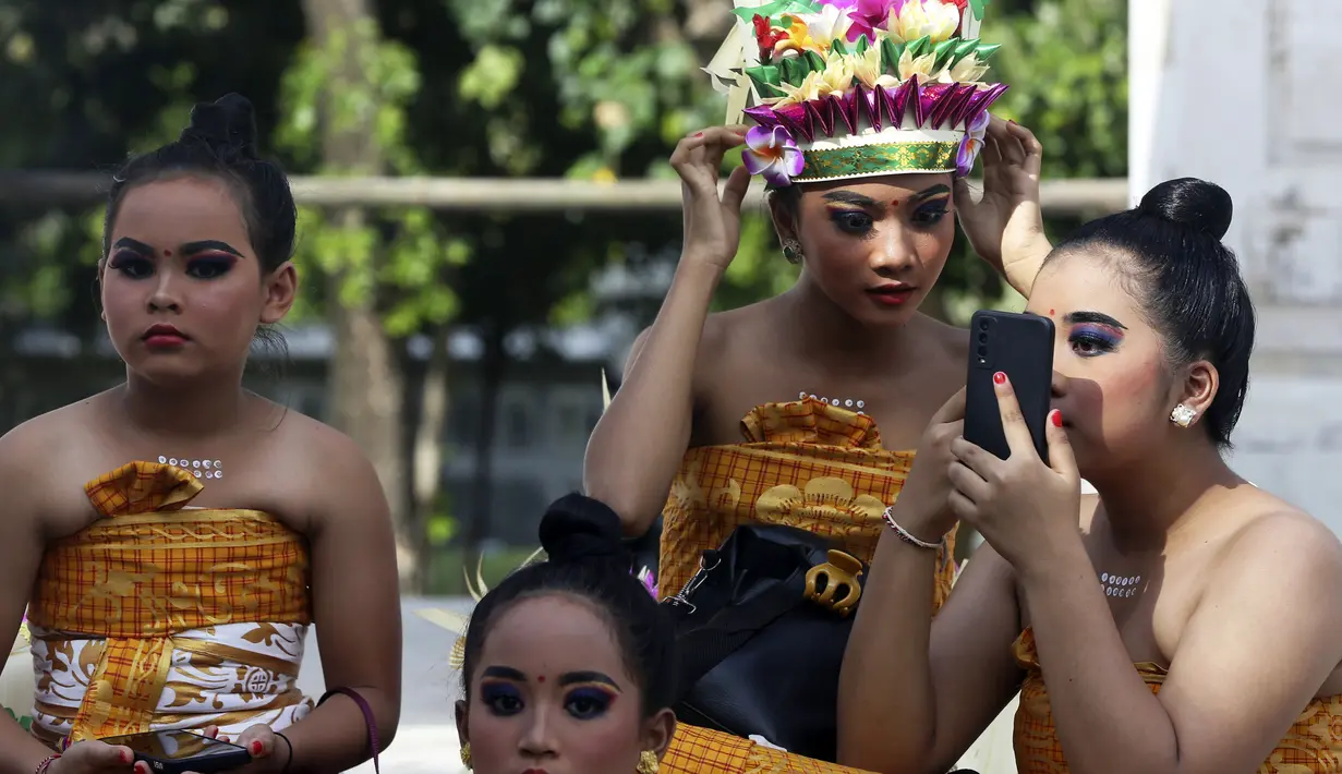 Penari wanita muda mempersiapkan diri untuk tampil pada perayaan Hari Raya Kuningan di Pura Sakenan, Bali, Sabtu (18/6/2022). Kuningan menandai hari terakhir perayaan Galungan, salah satu upacara keagamaan terbesar umat Hindu di Bali. (AP Photo/Firdia Lisnawati)