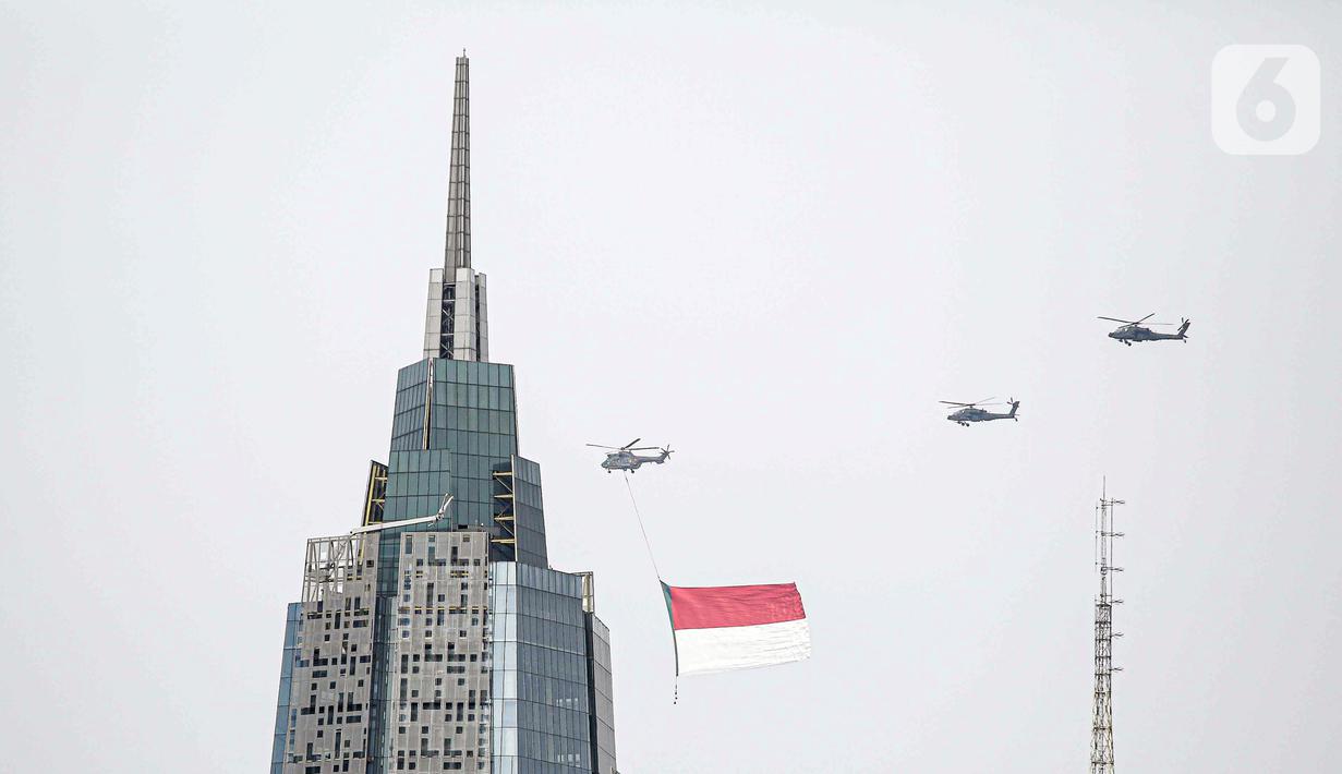 Helikopter TNI AU mengibarkan bendera Merah Putih raksasa di kawasan Gedung DPR RI, Jakarta, Selasa (5/10/2021). TNI AU mengerahkan enam helikopter yang membawa bendera Merah Putih serta bendera Trimatra raksasa. (Liputan6.com/Faizal Fanani)