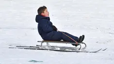 Seorang anak bermain kereta luncur selama hujan salju di taman Dunorlan di Tunbridge Wells, Inggris (27/2). Cuaca dingin di Siberia yang dijuluki "The Beast from the East" membuat suhu di sebagian Eropa menurun. (AFP Photo/Ben Stansall)