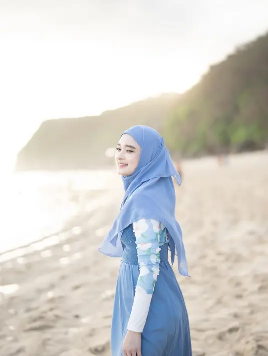 OOTD pantai ala Inara Rusli berikut ini dengan inner motif floral dan spaghetti strap dress warna biru cerah beri kesan anggun pada tampilan. [Instagram/mommy_starla]