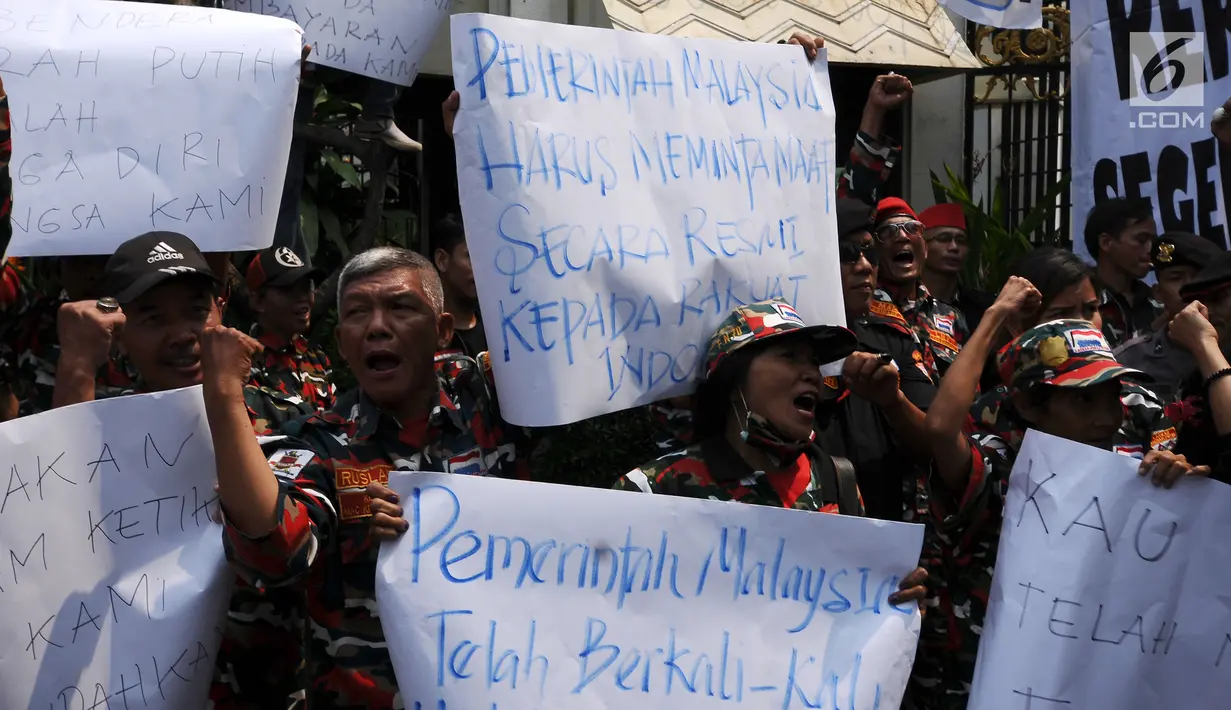 Peserta aksi membentangkan kertas pesan saat berunjuk rasa di depan Kedubes Malaysia, Jakarta, Senin (21/8). Aksi ini terkait kasus terbaliknya bendera Merah Putih pada buku panduan pelaksanaan SEA Games 2017. (Liputan6.com/Helmi Fithriansyah)