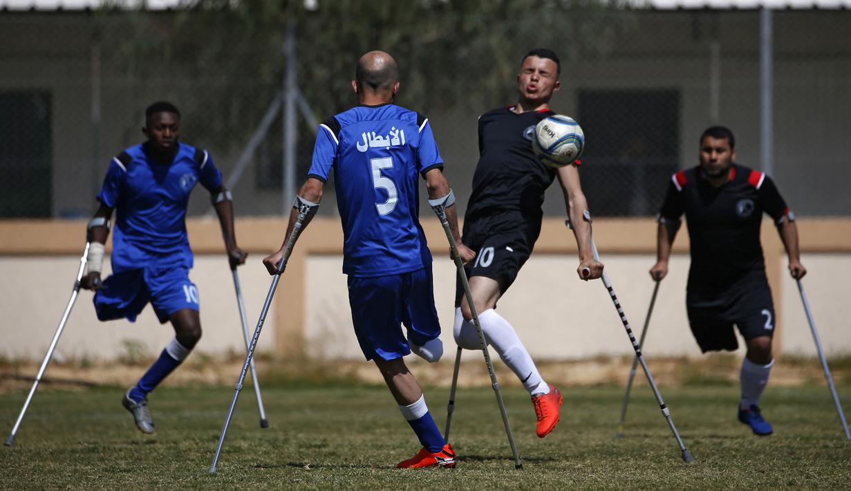 Seorang pemain klub Al-Jazeera (hitam) mengontrol bola dalam pertandingan final kejuaraan lokal sepak bola korban amputasi melawan Al-Abtal yang diselenggarakan oleh Komite Palang Merah Internasional (ICRC), di tengah pandemi COVID-19, di Kota Gaza, Palestina, (18/3/2021). (AFP/Mohammed Abed)