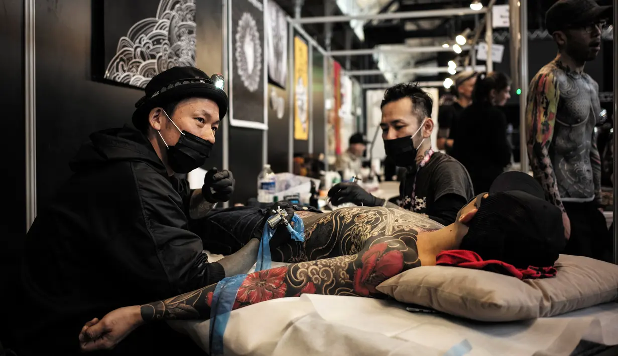 Seorang pria terbaring saat proses pembuatan tato di acara Paris Tattoo Convention di Grand Halle de la Villette, Paris, Prancis, Jumat (9/3). Paris Tattoo Convention berlangsung dari tanggal 9 sampai 11 Maret. (Philippe LOPEZ/AFP)