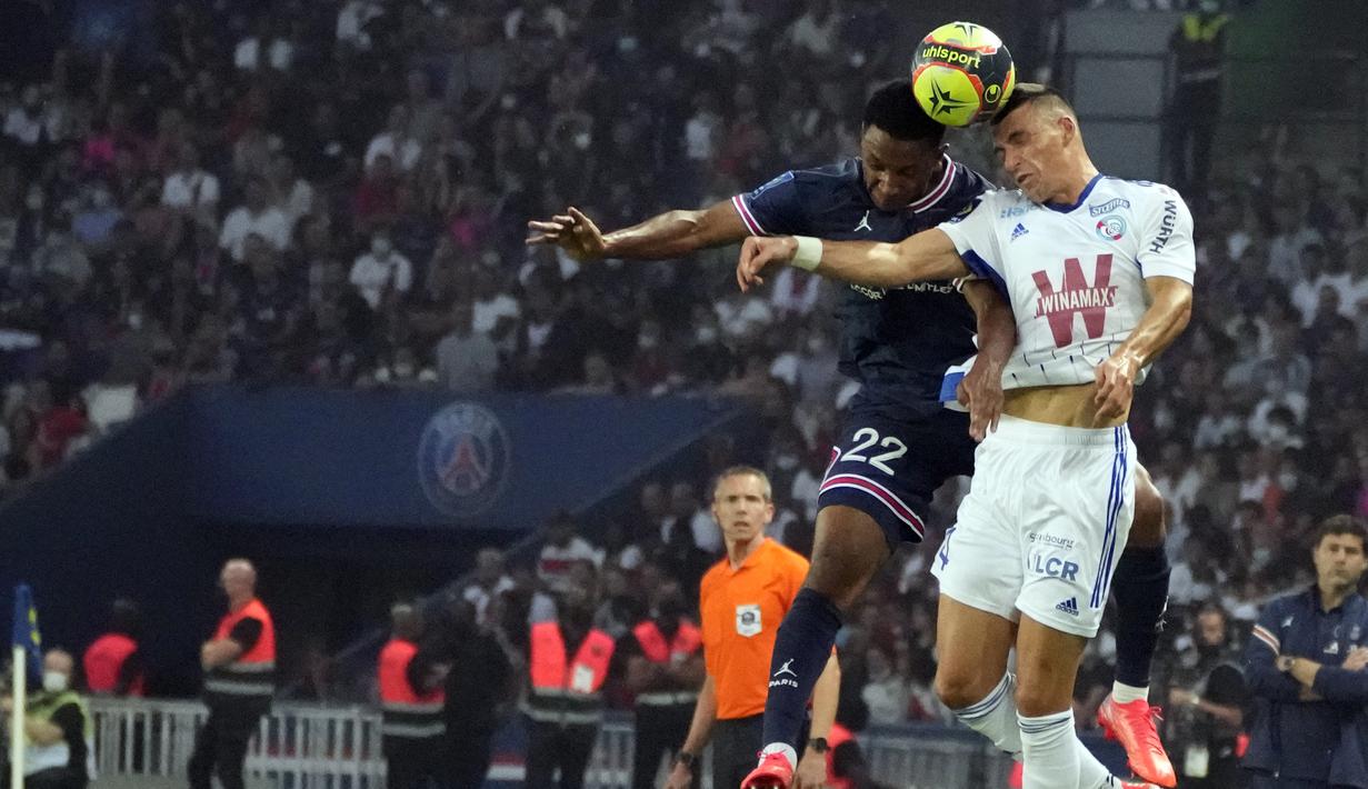 Bek Paris Saint-Germain (PSG) Abdou Diallo melompat untuk merebut bola dari bek Strasbourg Karol Filab pada laga pekan kedua Liga Prancis di Stadion Parc des Princes, Minggu (15/8/2021) dini hari WIB. PSG membekuk tamunya Strasbourg dengan skor 4-2. (AP Photo/Francois Mori)