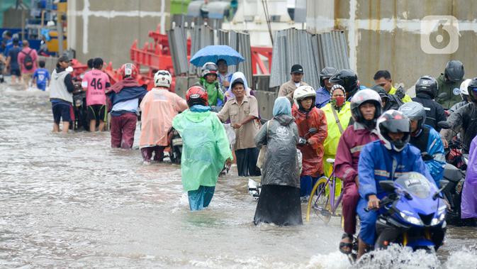 Sejumlah pengendara dan warga melintasi banjir di Jalan Raya Bekasi, Jakarta Timur, Selasa (25/2/2020). Banjir akibat hujan yang melanda Bekasi sejak Selasa (25/2) dini hari memutus beberapa titik jalan raya di wilayah setempat. (merdeka.com/Imam Buhori)