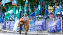 Seorang wanita mendorong sepedanya di samping bendera-bendera partai politik, Kuala Lumpur, Malaysia, Senin (7/5). Malaysia akan melangsungkan pemilu pada 9 Mei 2018. (AP Photo/Aaron Favila)