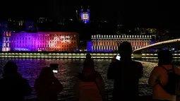 Pengunjung mengambil gambar sebuah bangunan yang diterangi cahaya dalam festival cahaya Fete des Lumieres di Lyon, Prancis, 7 Desember 2017. Festival selama empat hari itu menampilkan 50 instalasi buatan seniman lokal. (AFP PHOTO / PHILIPPE DESMAZES)