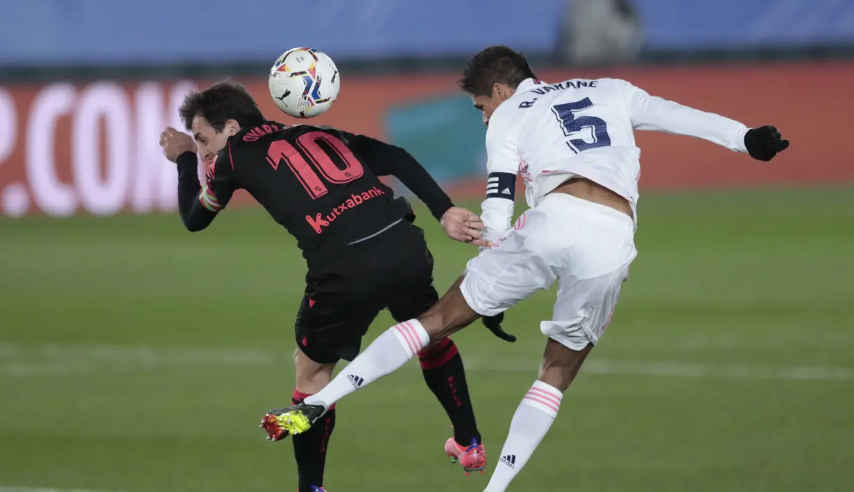 Bek Real Madrid, Raphael Varane (kanan) berduel udara dengan gelandang Real Sociedad, Mikel Oyarzabal dalam laga lanjutan Liga Spanyol 2020/21 pekan ke-25 di Alfredo di Stefano Stadium, Madrid, Senin (1/3/2021). Real Madrid bermain imbang 1-1 dengan Real Sociedad. (AP/Bernat Armangue)