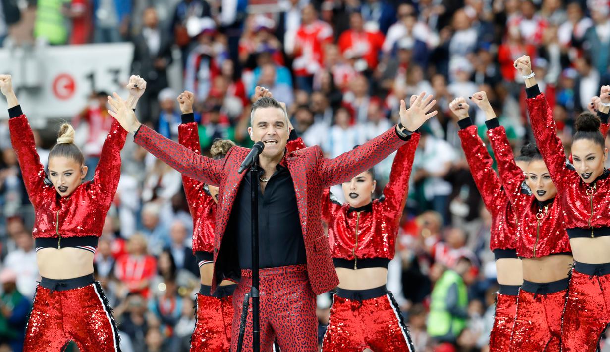 Penampilan penyanyi Inggris, Robbie Williams pada upacara pembukaan Piala Dunia 2018 di Stadion Luzhniki, Moskow, Kamis (14/6). Robbie dikelilingi para penari dengan atasan berkilauan merah terang yang menambah meriah penampilan. (AP/Antonio Calanni)