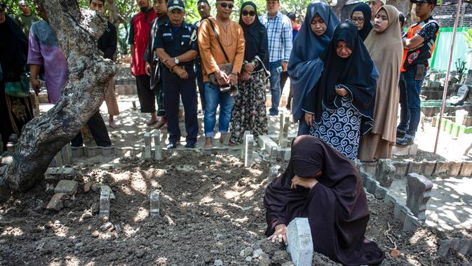 Lyan Kurniawati, istri dari penyelam Syachrul Anto yang meninggal dunia kala melakukan evakuasi jatuhnya pesawat Lion Air PK-LQP, berdoa saat pemakaman di Surabaya, Jawa Timur, Sabtu (3/11). Syachrul Anto meninggal karena dekompresi. (JUNI KRISWANTO/AFP)
