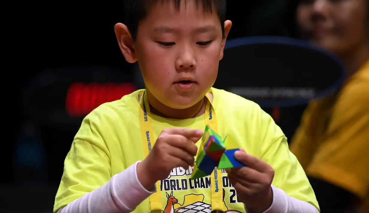 Seorang anak semangat memecahkan permainan rubik pada kejuaraan kubus Rubik Dunia di Melbourne, Australia (12/7/2019). Kejuaraan Dunia diadakan setiap dua tahun dan telah menarik 905 pesaing dari seluruh dunia yang bersaing dalam 18 acara yang berbeda. (AFP Photo/William West)